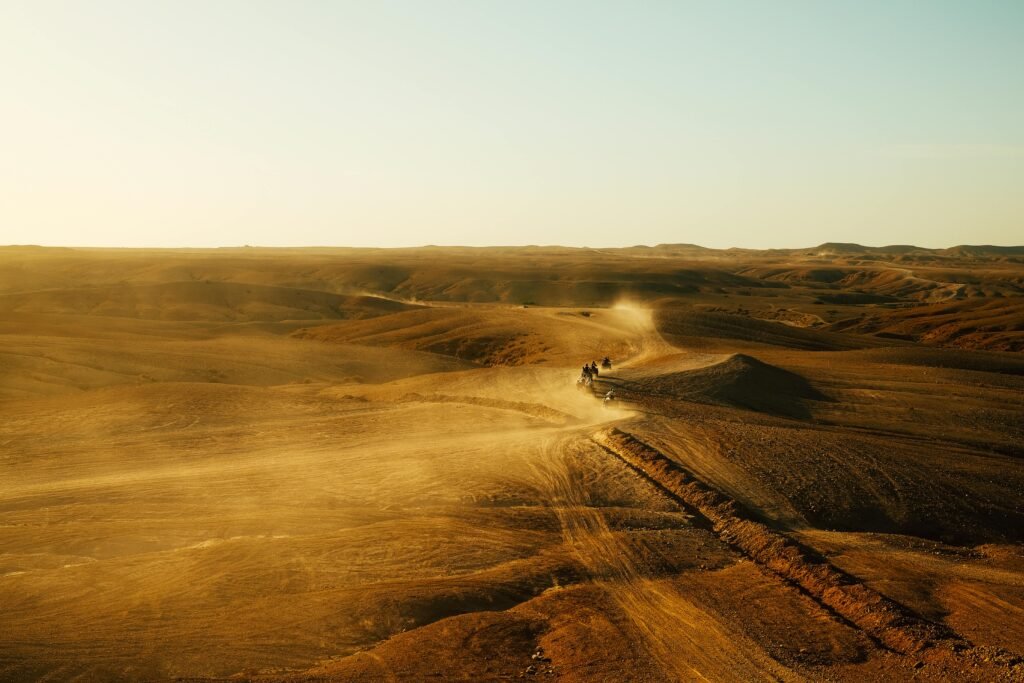Desert expedition with all-terrain vehicles traversing expansive dunes under a clear sky.