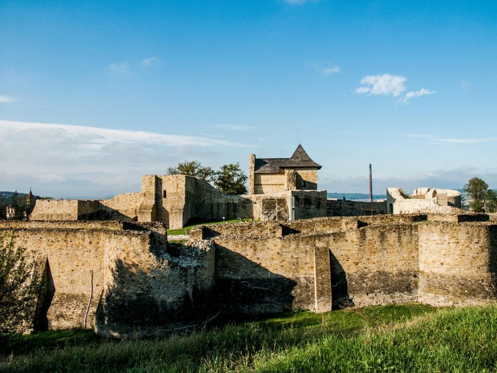 Explore the serene beauty of ancient castle ruins against a vibrant blue sky, surrounded by lush greenery.