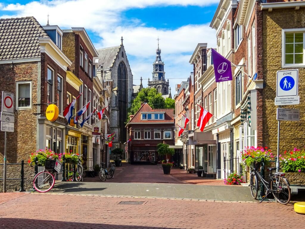 Picturesque street view in Gouda, Netherlands featuring church, flags, and bicycles.