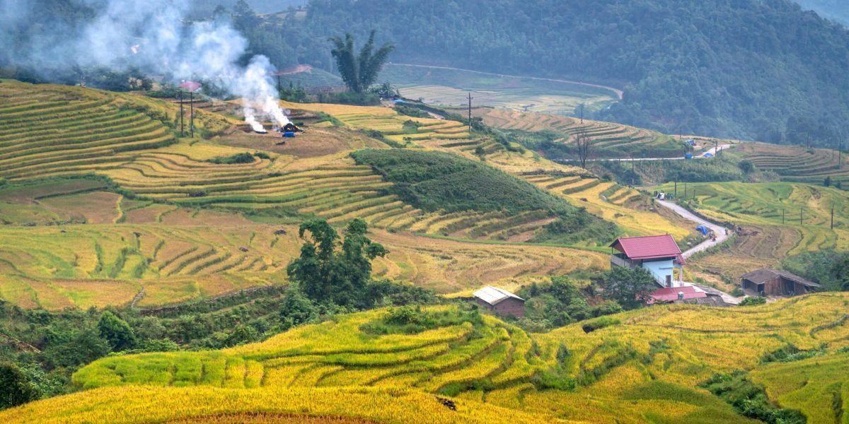 Beautiful rice terraces with smoke rising in a serene mountain valley landscape.