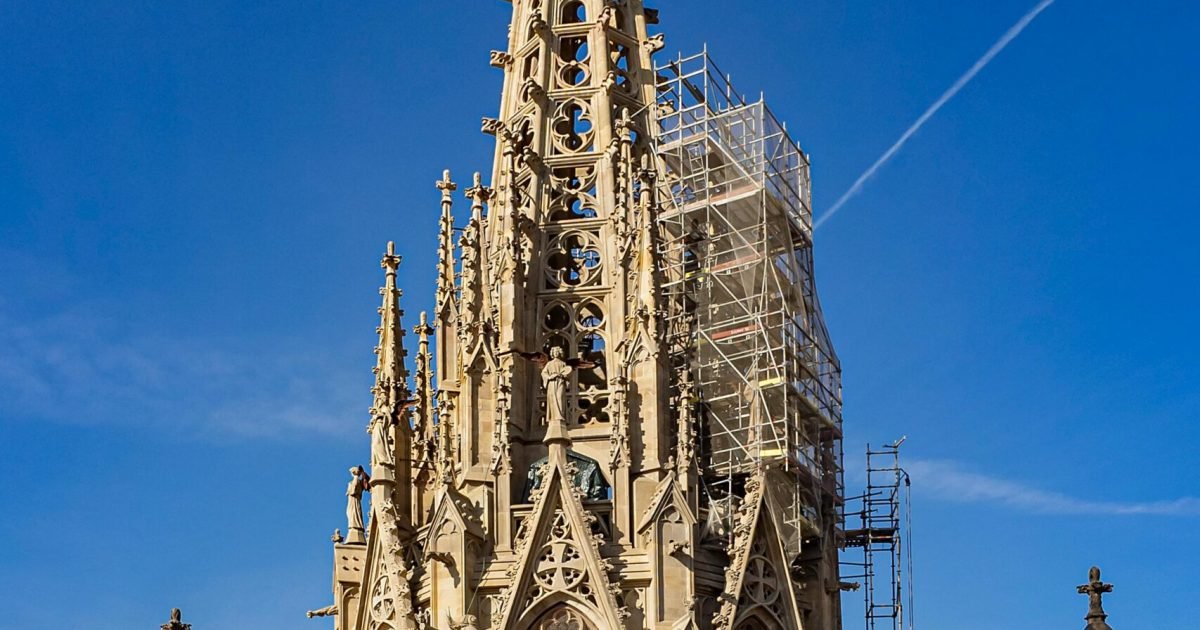 The intricate Gothic spire of Barcelona Cathedral under a clear blue sky, showcasing stunning architecture.