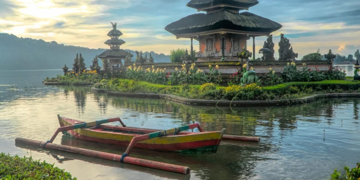 Scenic view of Ulun Danu Beratan Temple with boats on Bratan Lake, Bali at dawn.