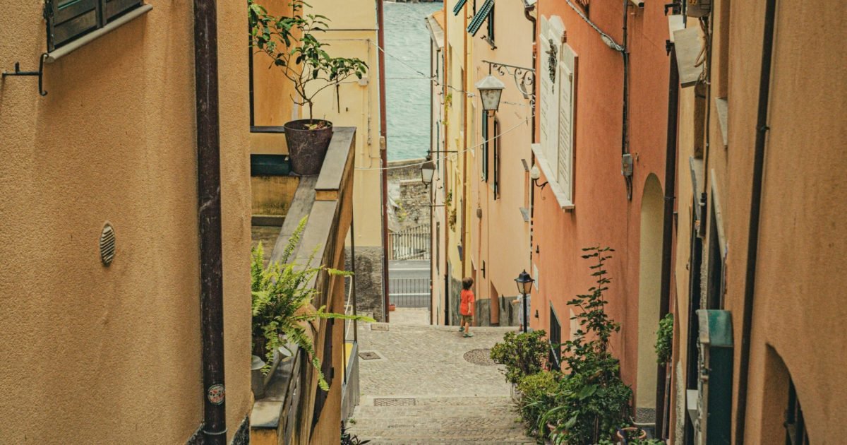 A picturesque view down a narrow alleyway leading to the sea in a historic coastal village.